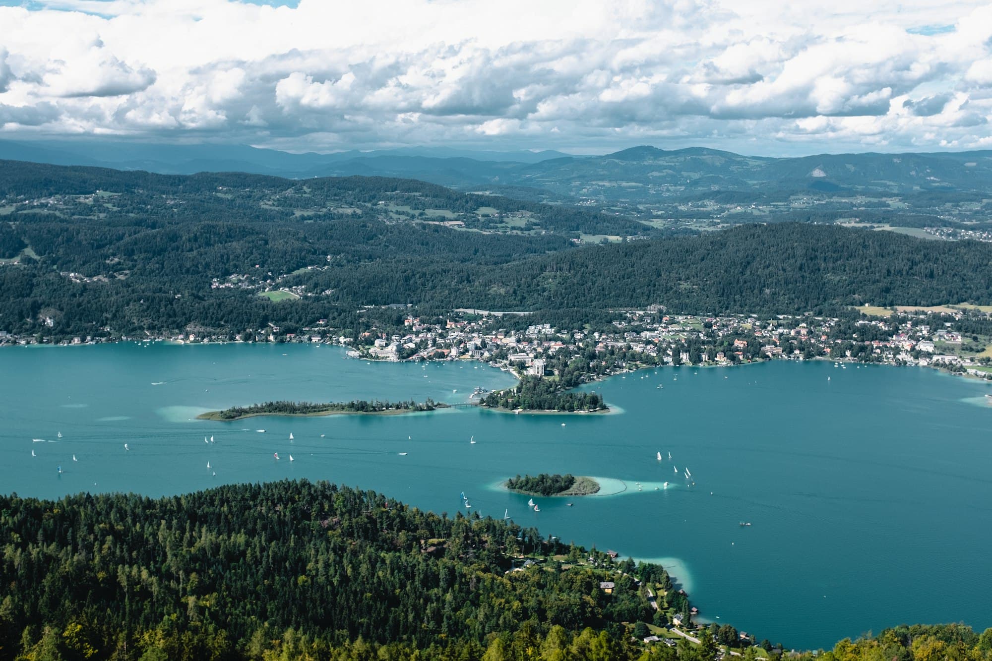 Blick von oben auf den Wörthersee in Kärnten: türkisblaues Wasser und bewaldete Ufer bei Klagenfurt.